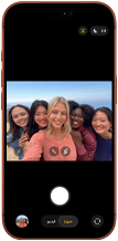 iPhone 17 Pro in Cosmic Orange, front, screen shows Center Stage front camera open with a group selfie of five people centered in frame