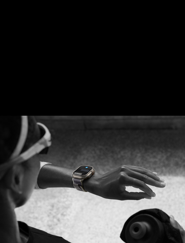صورة لعداءٍ ينظر إلى ساعة Apple Watch Ultra 2 على معصمه الأيسر، ويقوم بحركة النقر مرتين باستخدام إصبعي السبابة والإبهام في يده اليسرى