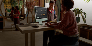 Two people in a well-lit room, viewing products on the iMac nano-texture glass display